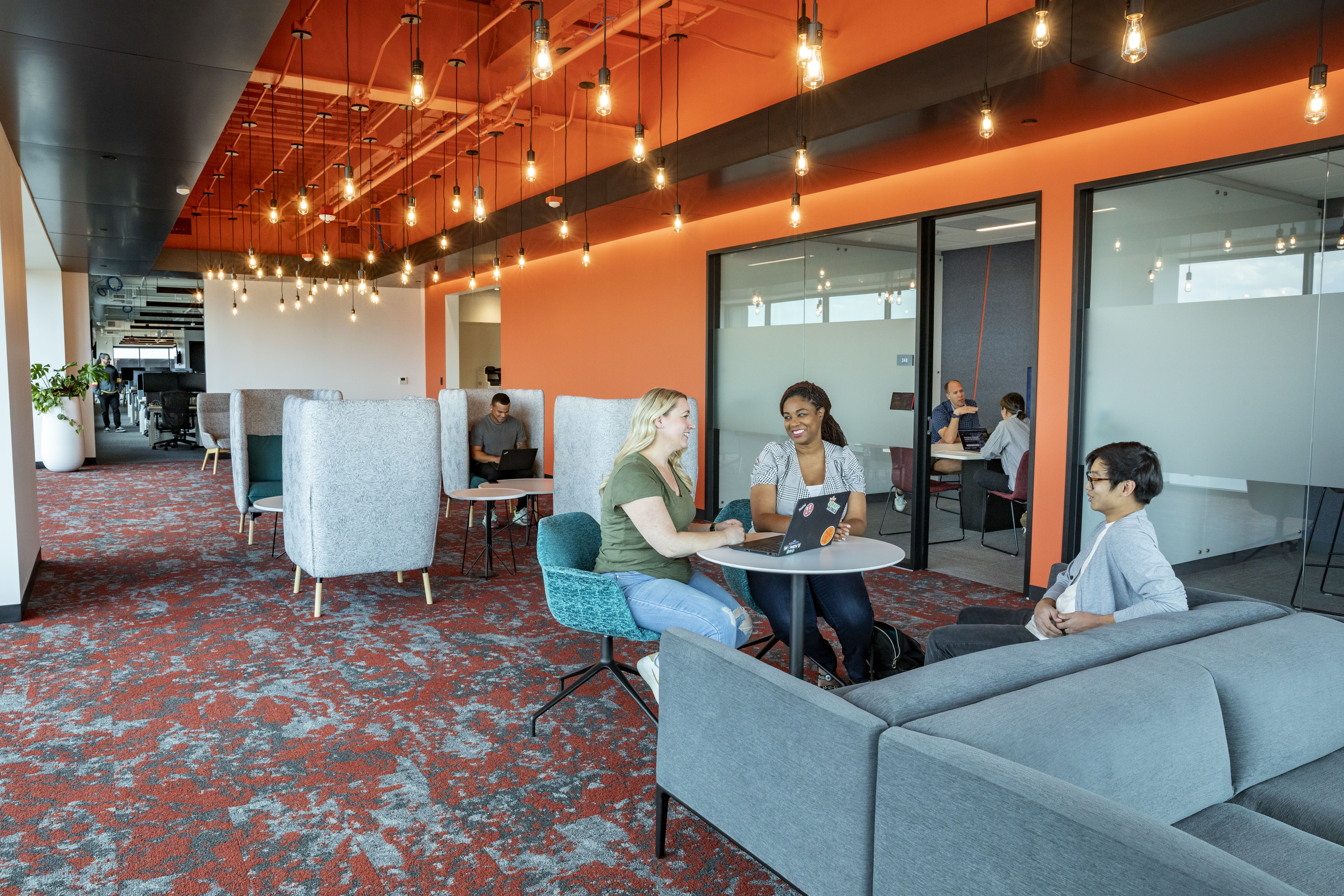 a group of people sitting at tables in a room with orange walls