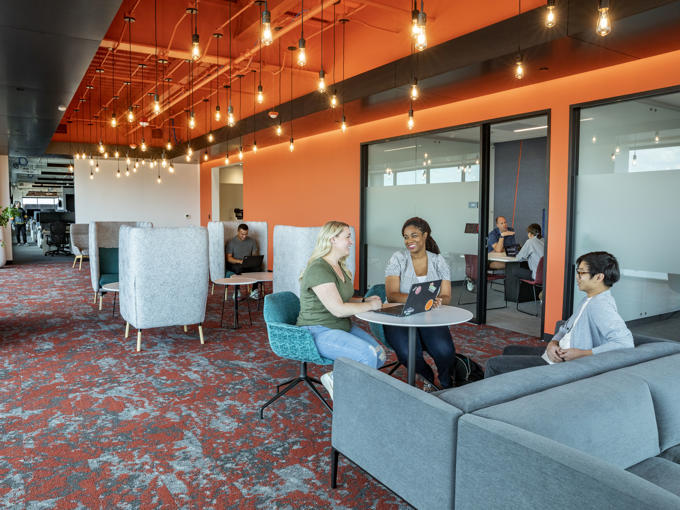a group of people sitting at tables in a room with orange walls