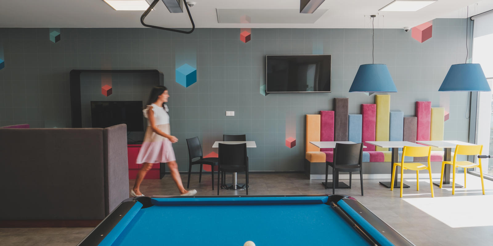 a woman walking in a room with a pool table