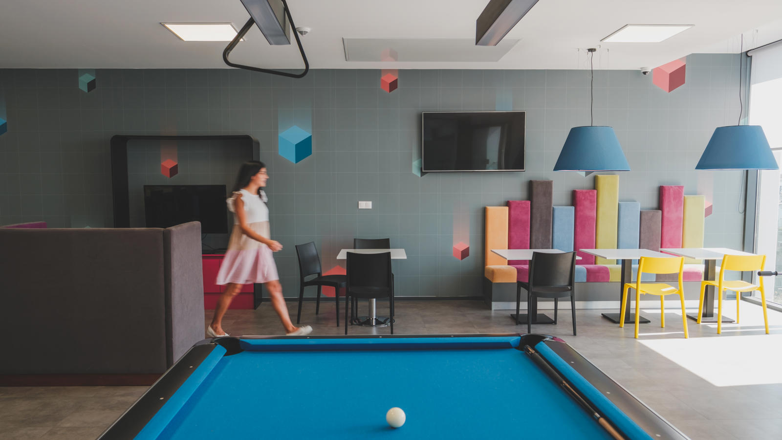 a woman walking in a room with a pool table