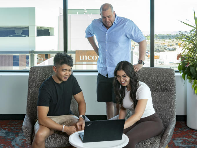 a group of people sitting in chairs looking at a laptop