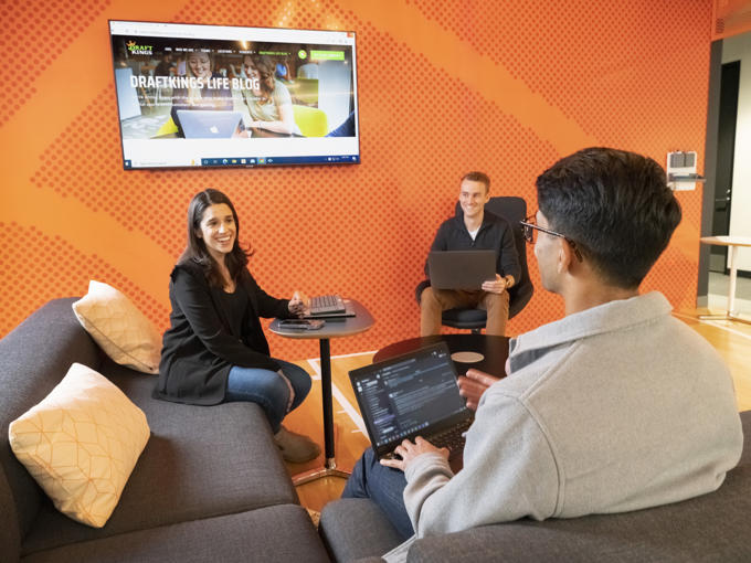 a group of people sitting around a table and laptops