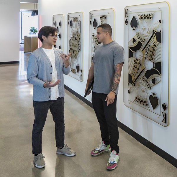 two men standing in front of a wall with cards on it