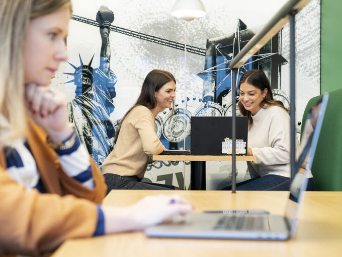 a group of women sitting at a table with a laptop