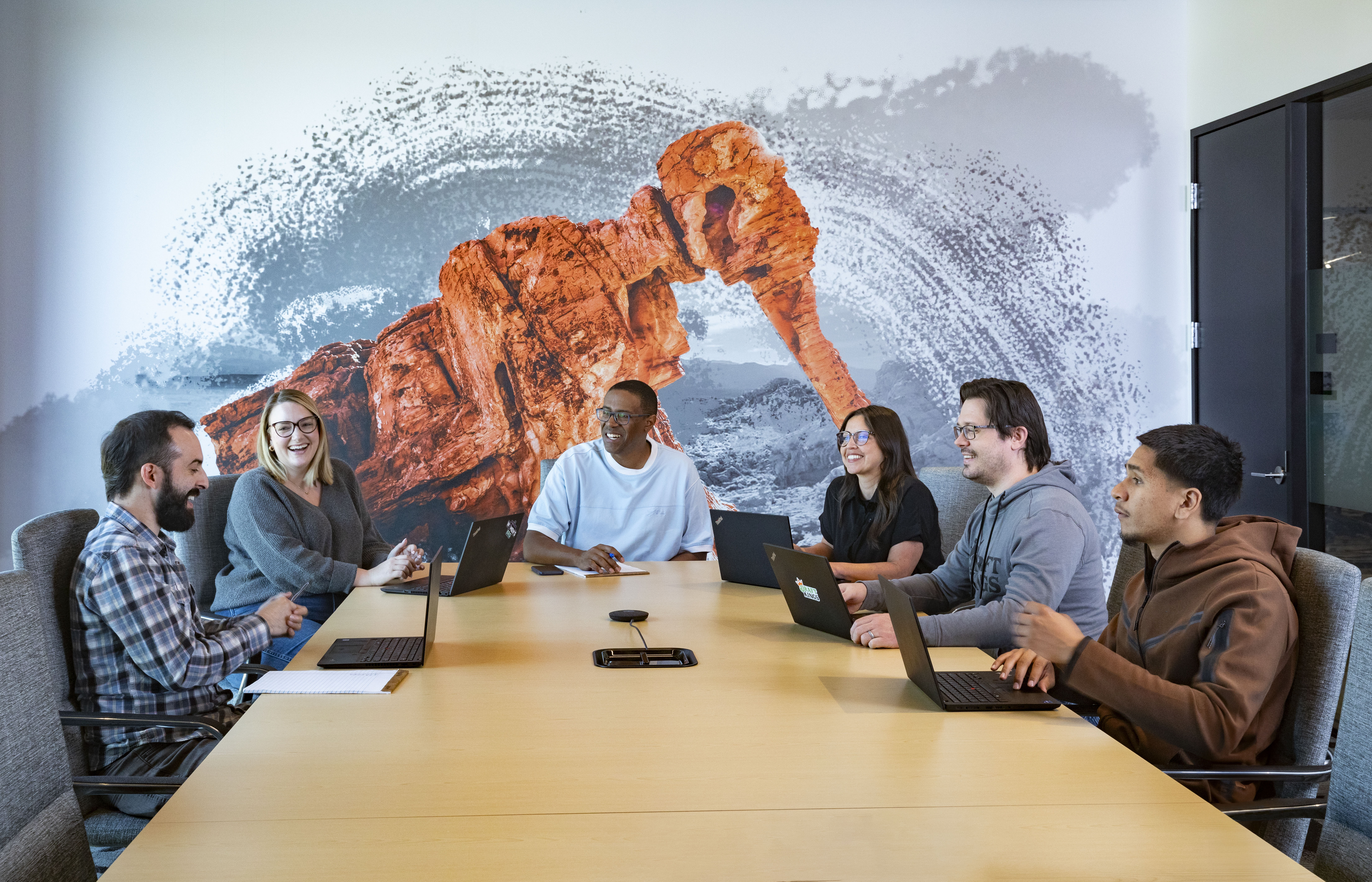 a group of people sitting around a table with laptops