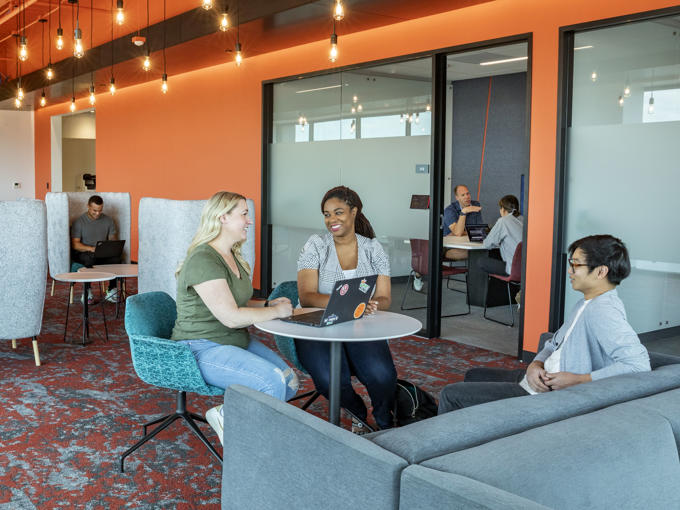 a group of people sitting at tables in a room with orange walls