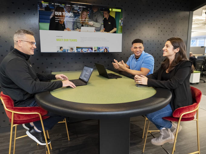 a group of people sitting at a table with laptops