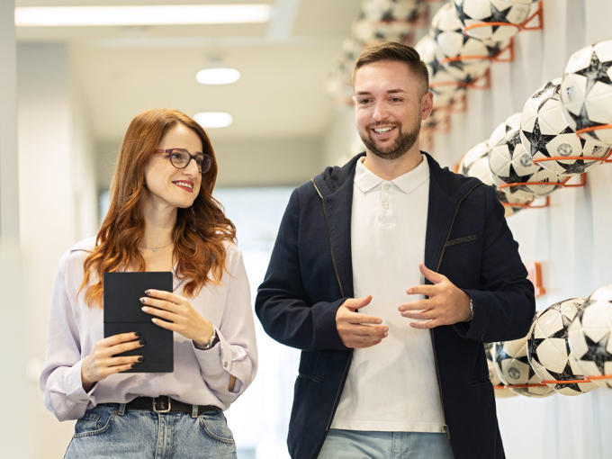 a man and woman walking in a hallway with football balls