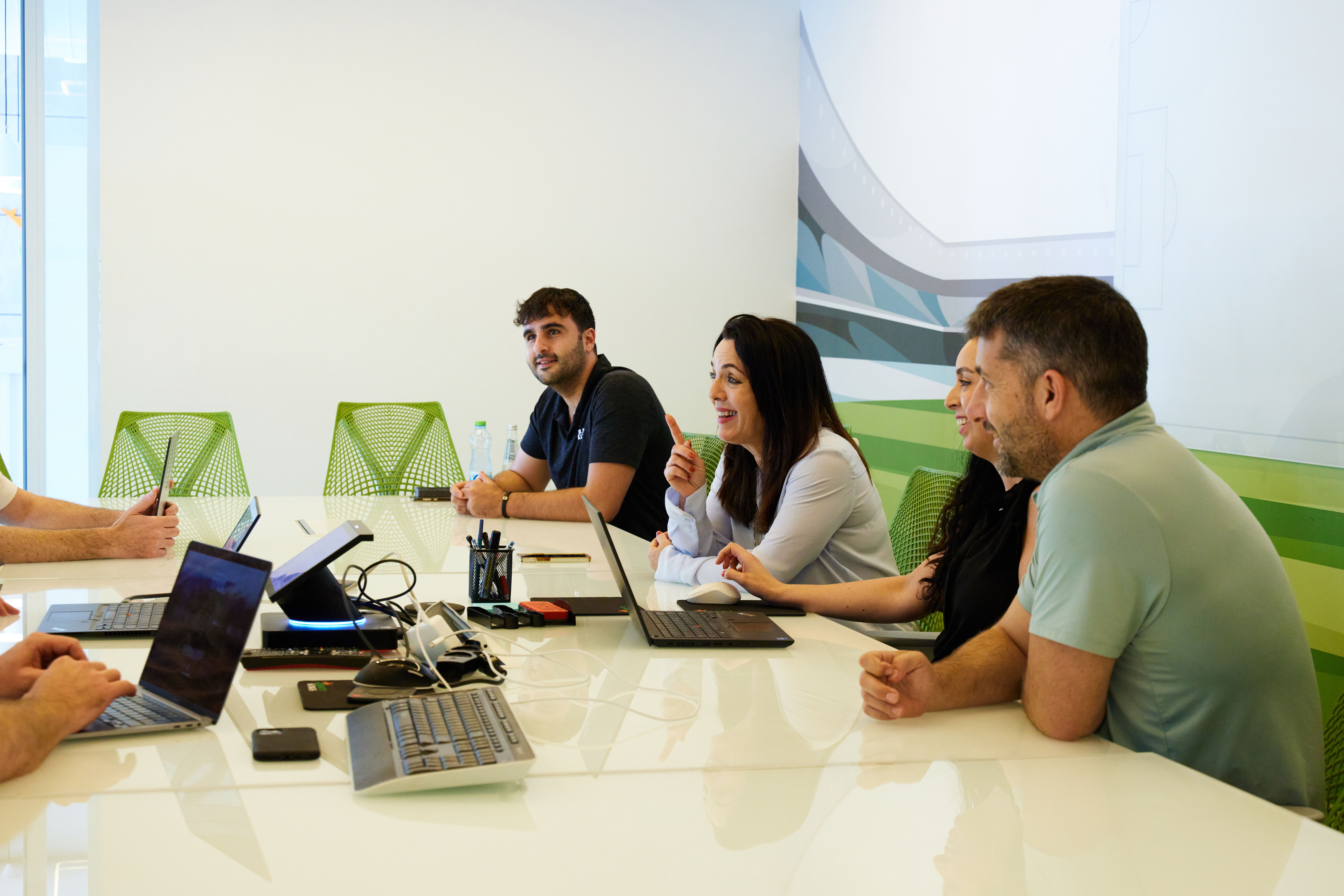 a group of people sitting at a table with laptops