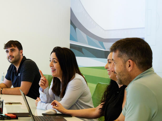 a group of people sitting at a table with laptops