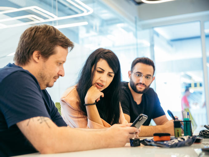 a group of people sitting at a table looking at a phone