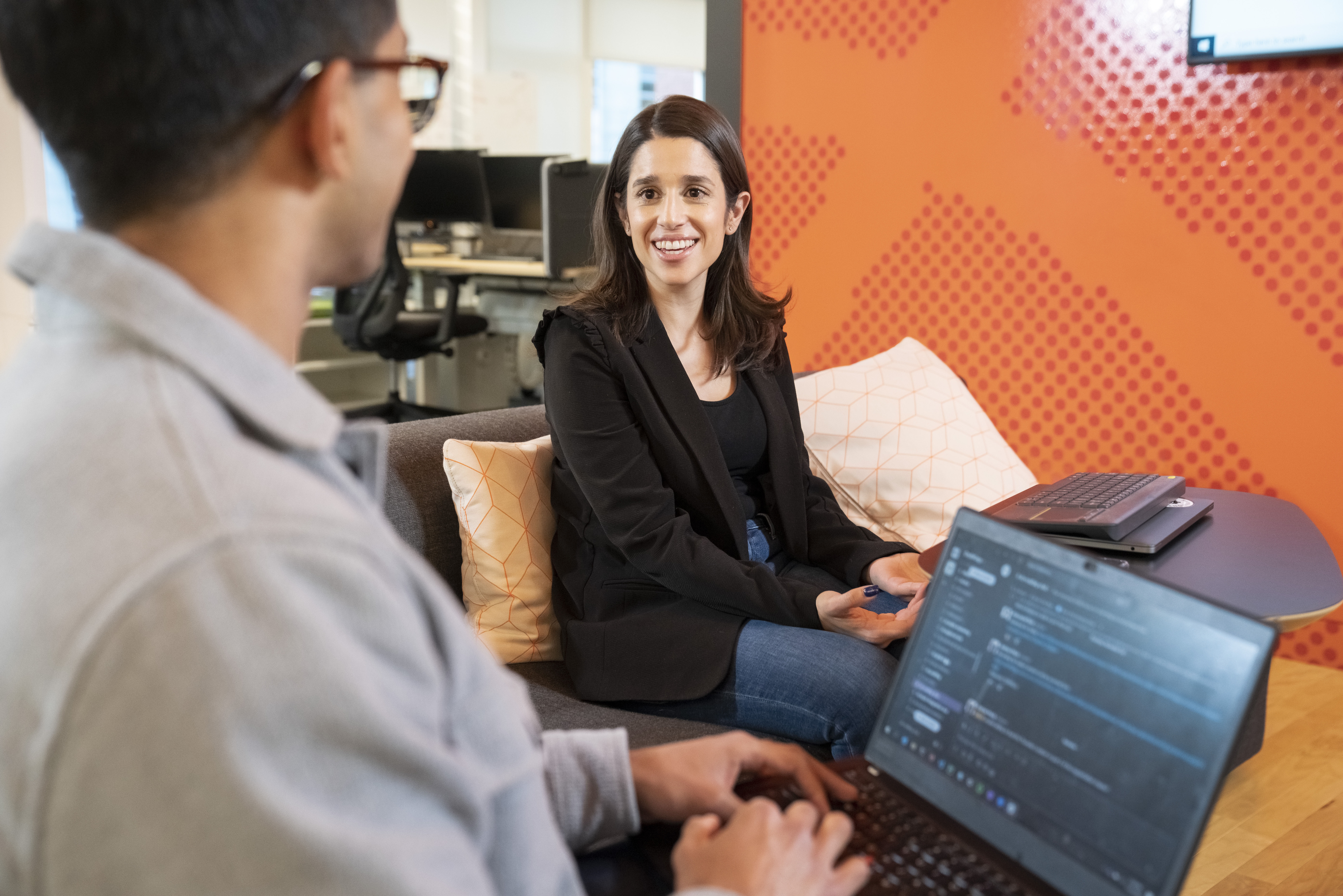 a man and woman sitting on a couch with laptops