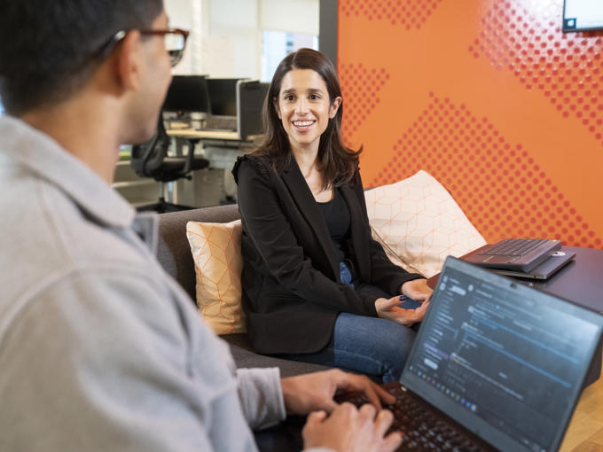 a man and woman sitting on a couch with laptops